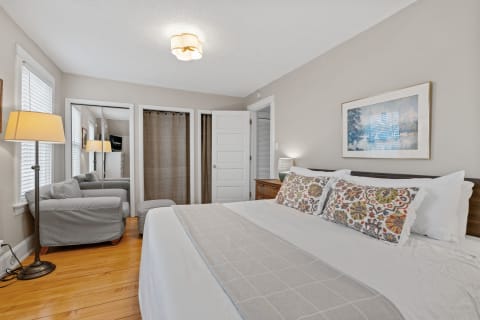 Cozy bedroom with a large bed, gray armchair, and decorative pillows.