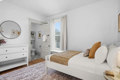Inviting bedroom with single bed, dresser, and bathroom door in view.