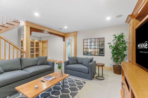 Cozy living room with gray sofas, wooden furnishings, and a decorative mirror.