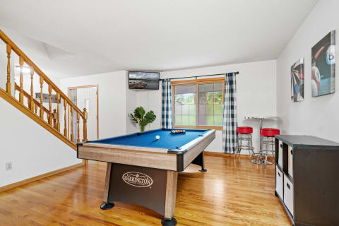 Game room with a pool table, a staircase, and a small dining area.