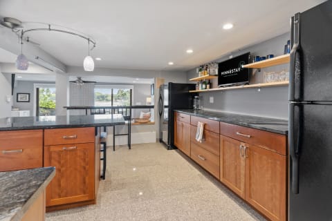 Modern kitchen with wooden cabinets and granite countertops overlooking a serene view.