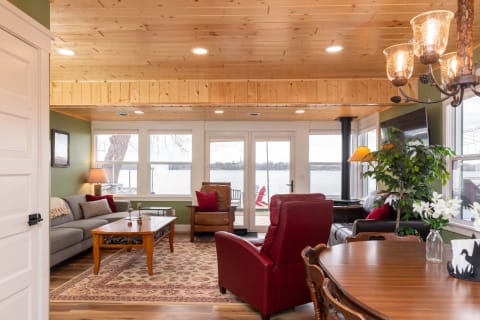 A warm and inviting lakeside living room with a gray sofa, wooden furniture, and a view of the lake.