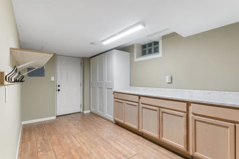 A clean laundry room featuring a countertop and storage cabinets.