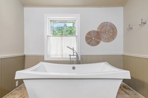 Modern bathroom with a freestanding bathtub and natural light.
