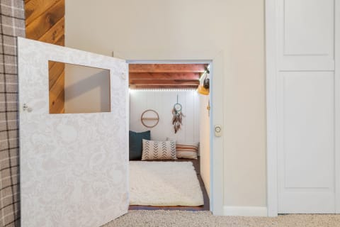 A small nook with cushions and decor, viewed through a patterned white door.