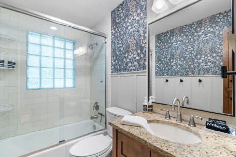 Interior of a modern bathroom featuring a glass block window and stylish floral wallpaper.