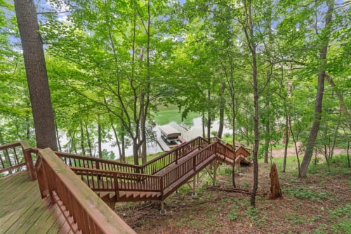 Wooden stairs wind through lush forest canopy leading to private waterfront dock and lake access below.