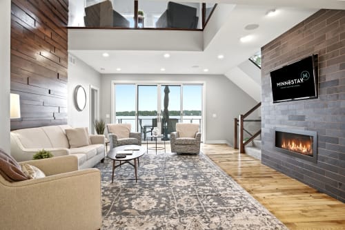 Sink into the plush sofa and feel the warmth of the modern fireplace as natural light floods your open-concept retreat, with lake views beckoning from beyond the glass doors.