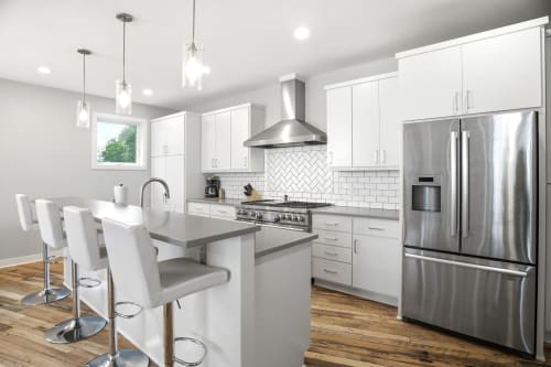Step into your sleek, modern kitchen with pristine white cabinetry, gleaming stainless appliances, and a spacious island perfect for morning coffee or meal prep. Sunlight fills the space through bright windows as you plan your culinary adventures.