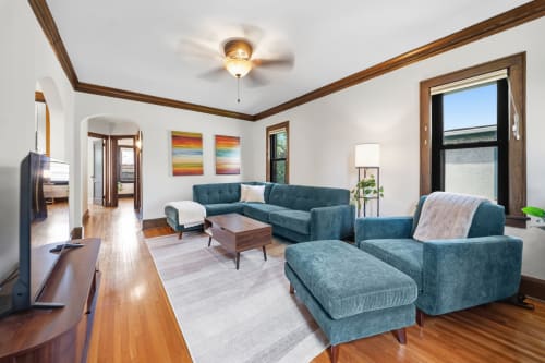 Sink into plush teal seating in your light-filled living room, where warm wood accents and vibrant art create the perfect backdrop for unwinding after exploring the area.