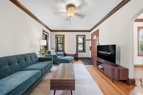 Step into your inviting living room, where rich hardwood floors, elegant wood trim, and comfortable teal furnishings create a warm and stylish retreat perfect for relaxing after a day of exploring.
