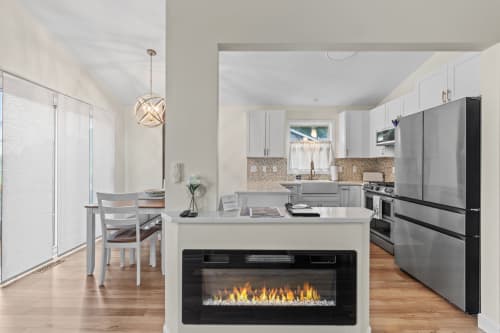 Gather around your stunning modern kitchen with a cozy fireplace island, stainless steel appliances, and elegant pendant lighting creating the perfect culinary haven.