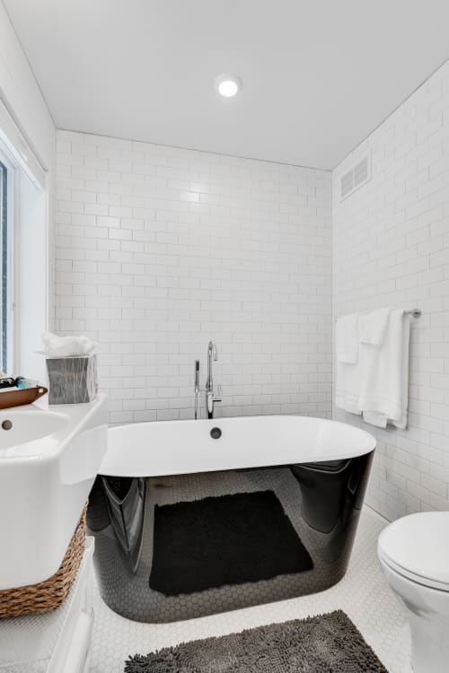 Sink into this elegant freestanding tub surrounded by crisp white subway tiles, where fluffy towels await your relaxing soak.