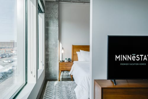 Unwind in your modern bedroom featuring floor-to-ceiling windows, crisp white linens, and warm wood accents that create the perfect urban retreat.