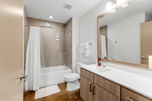 Step into your modern bathroom featuring sleek tiled walls, a relaxing tub-shower combo, and contemporary finishes for your comfort.