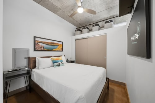 Unwind in your cozy urban loft with exposed concrete ceilings, a ceiling fan, and crisp linens welcoming you after a day of exploring.