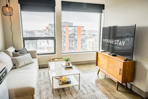 Unwind in this stylish living space with panoramic city views through floor-to-ceiling windows and modern entertainment setup.