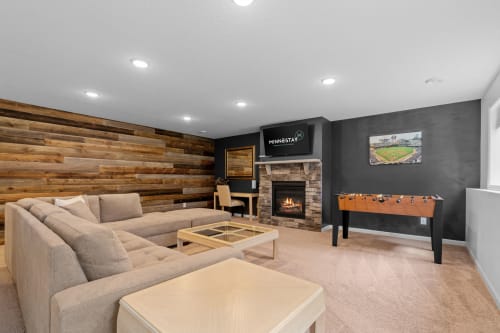 Unwind in your private game room featuring a cozy fireplace, plush sectional seating, and foosball table for endless entertainment.