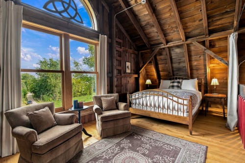 Curl up in your cozy reading nook by expansive windows that frame peaceful countryside views, then drift off beneath vaulted timber ceilings and soft lamplight.
