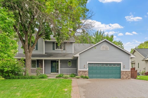 Charming two-story home with welcoming covered porch and mature landscaping in peaceful residential neighborhood setting.
