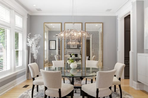 Step into an elegant dining space where soft gray tones, plush seating, and a stunning crystal chandelier create the perfect setting for memorable meals with loved ones.
